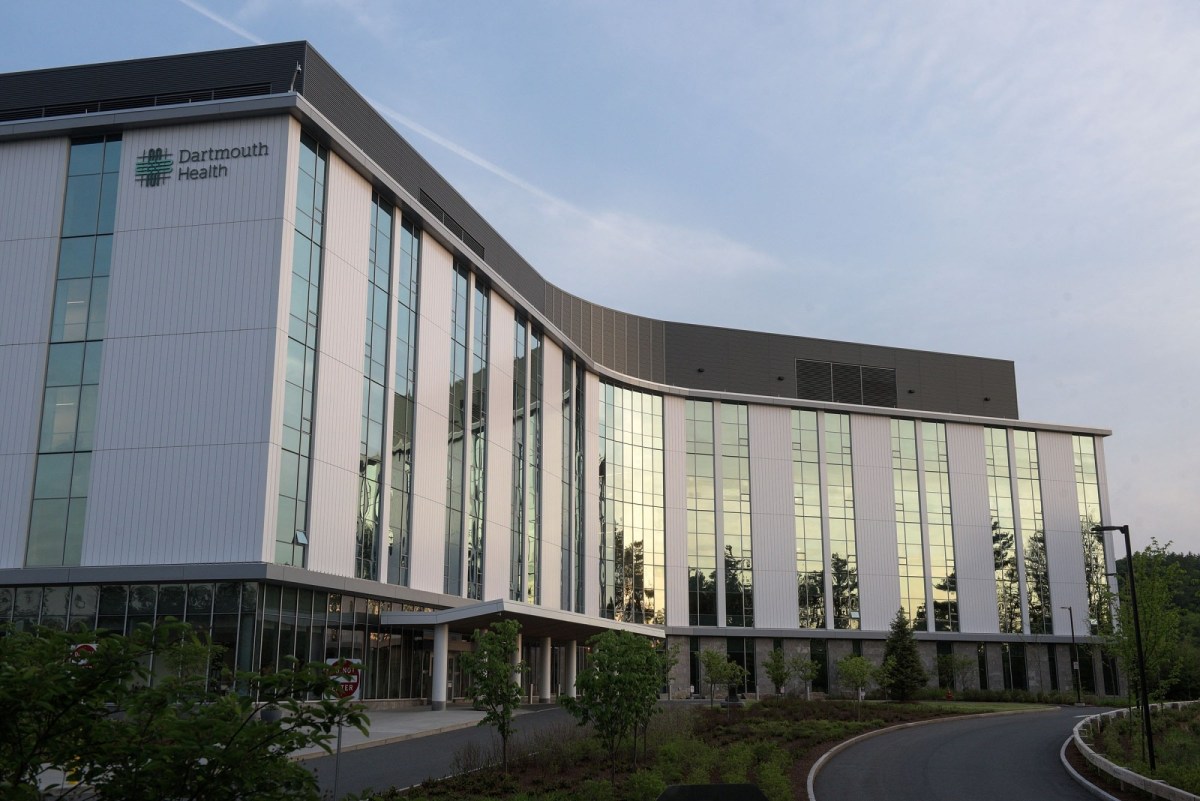 A modern multi-story building with large windows and the Dartmouth Health logo, surrounded by greenery and a curved driveway.