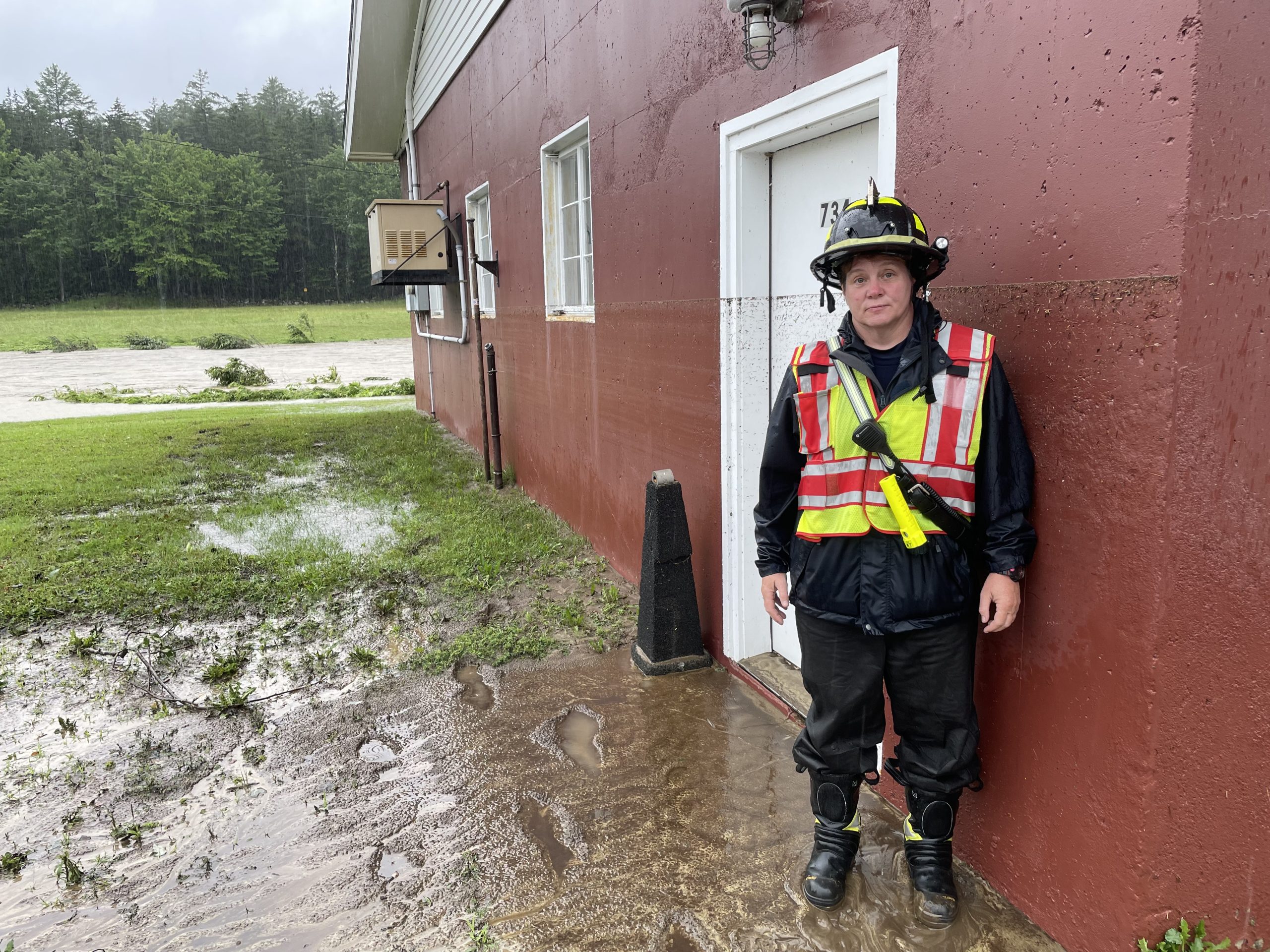 a firefighter standing next to a flooded building.