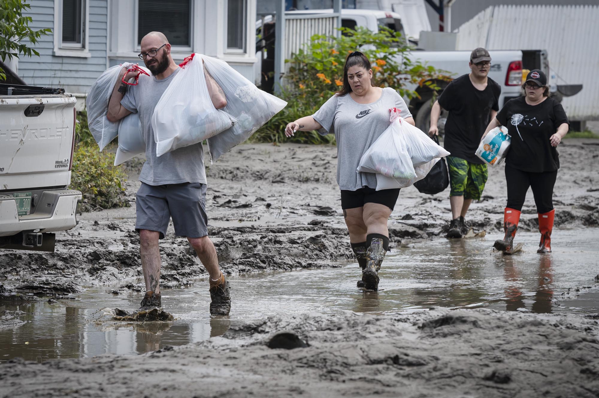 a group of people carrying bags through a muddy street.