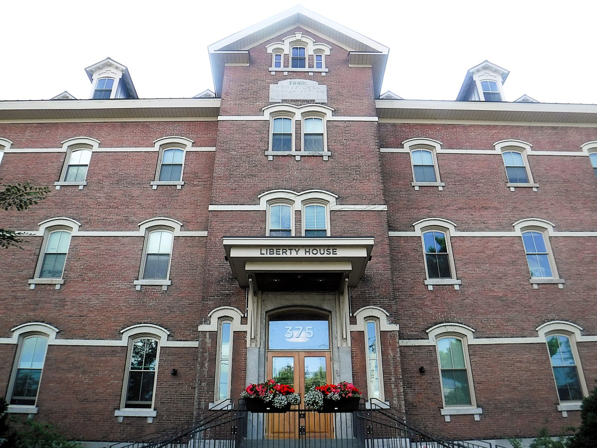 A three-story brick building labeled "Liberty House" with arched windows, a central entrance marked "375," and flower boxes under the front windows.