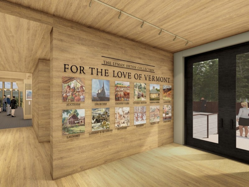 Wood-paneled museum hallway with a display titled "For the Love of Vermont" featuring eight vintage-style posters and people visible through glass doors and windows.