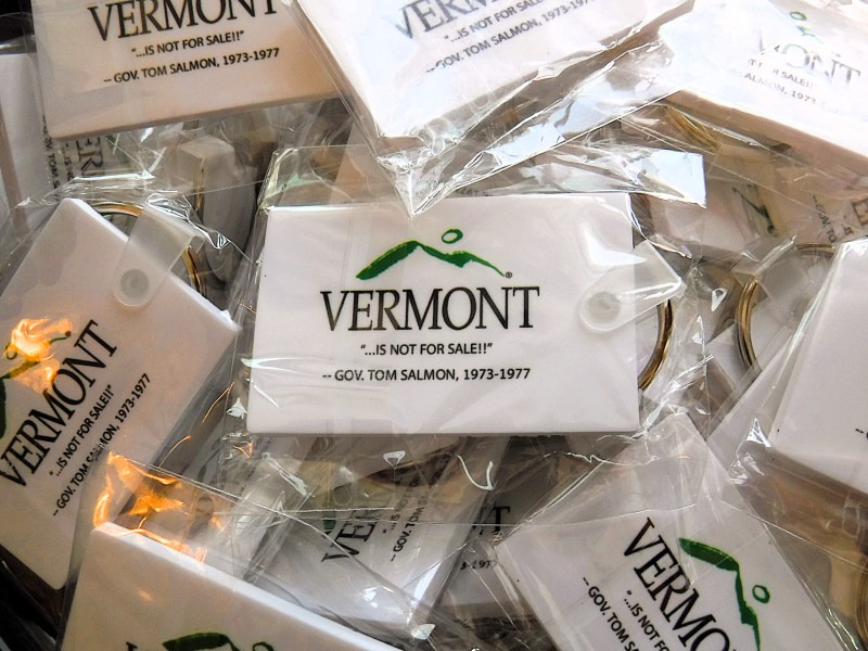 A pile of rectangular keychains in plastic wrappers, each displaying the Vermont state logo and the slogan: "VERMONT ...IS NOT FOR SALE! - GOV. TOM SALMON, 1973-1977".