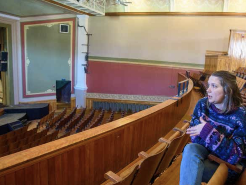 A woman sits in a theater.